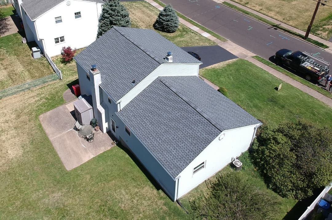 Aerial view of a single-family home with a gray roof and well-maintained yard.